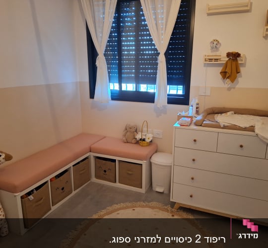 כריות ורודות על ספסל ליד שידת החתלה